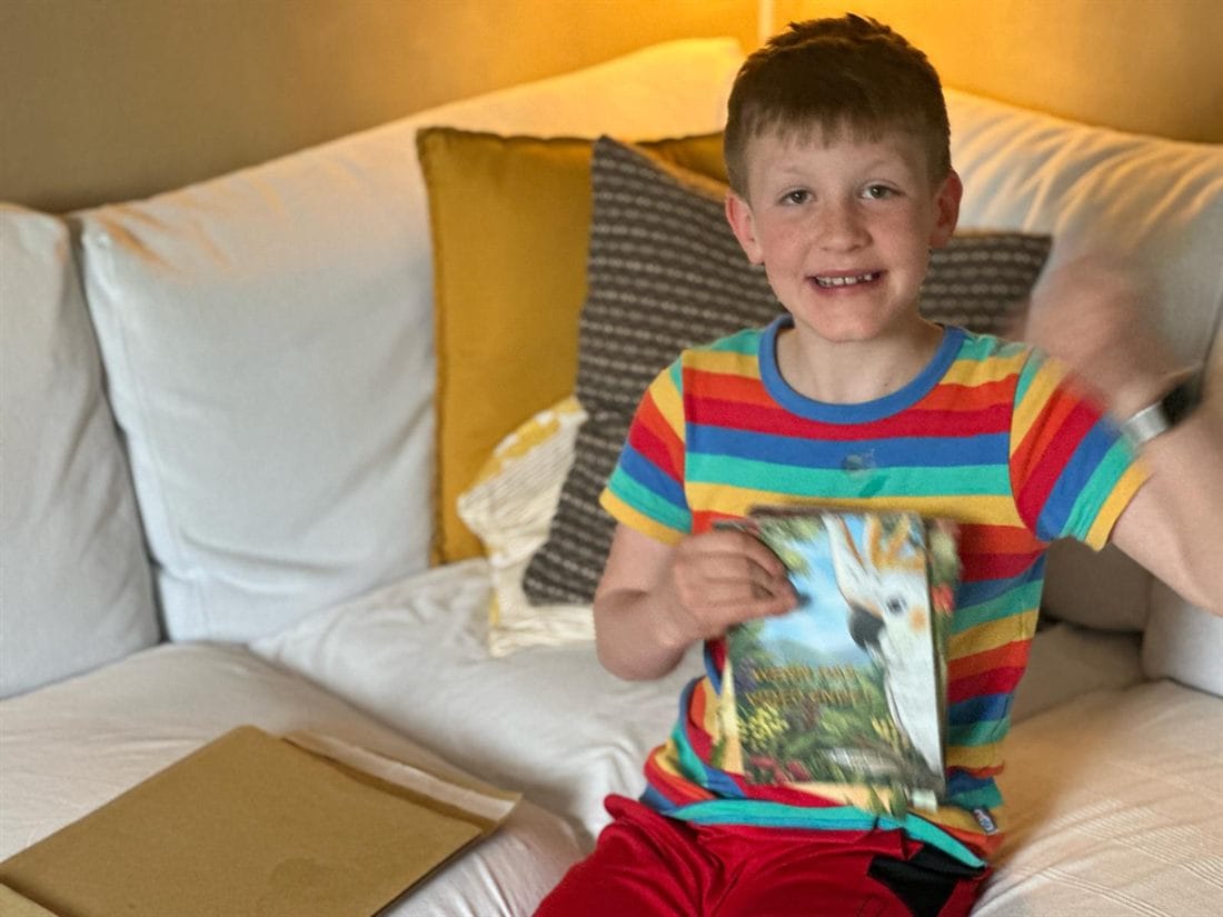 Lachendes Kind mit einem WILD-Moments-Buch